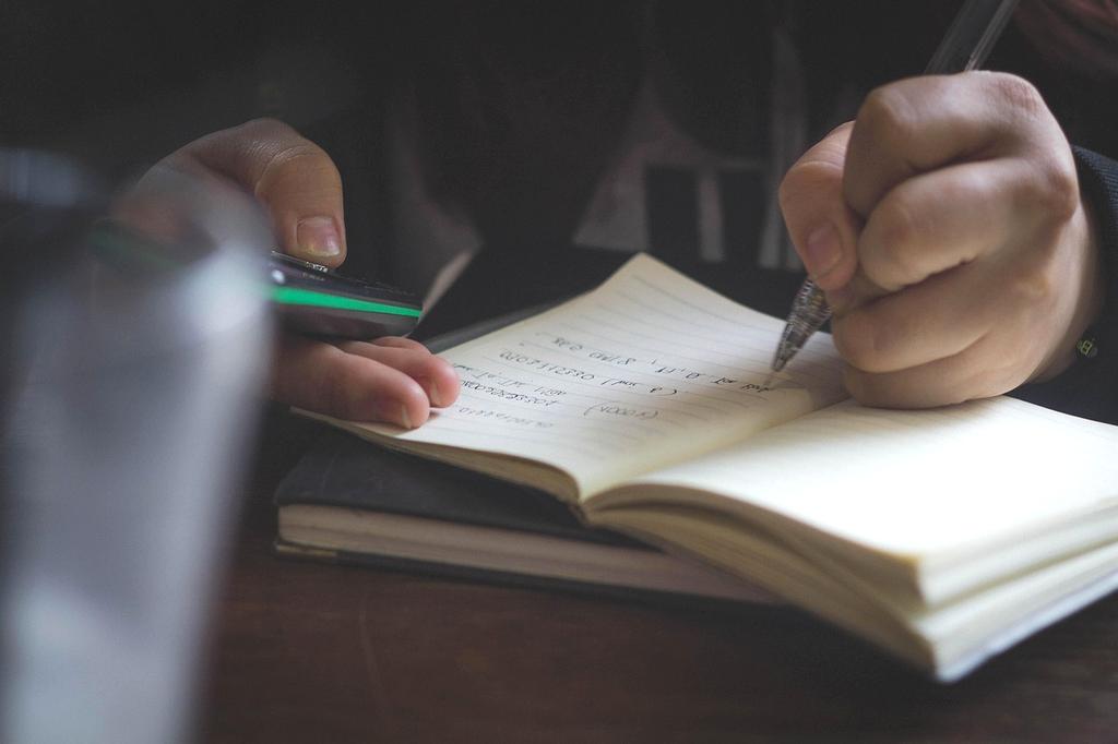 Close-up of hands holding journal and pen for personal development notes